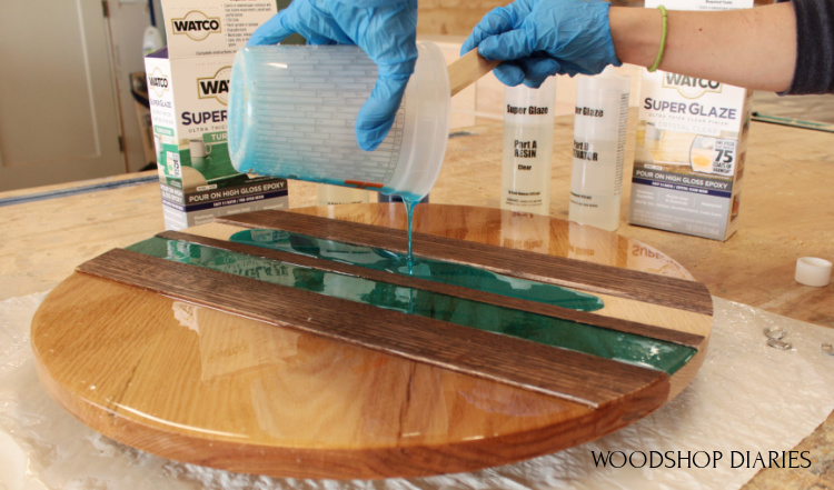 Pouring turquoise epoxy between shims on red oak wooden circle