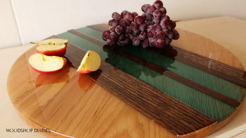 Round red oak wood and epoxy plate with multicolored resin used as a lazy susan with apples and grapes on top