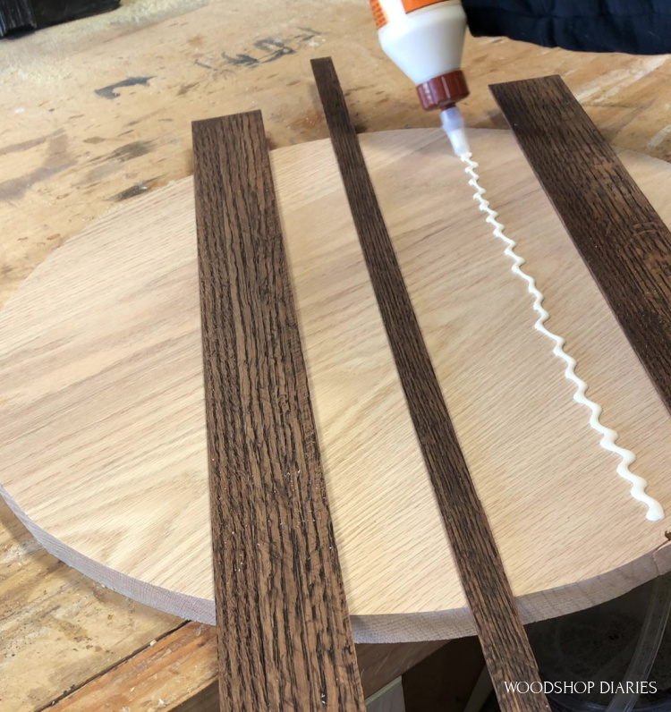 Applying glue to attach stained shims to wooden circle