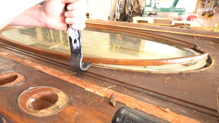 Using prybar to remove trim around old wood door glass panel
