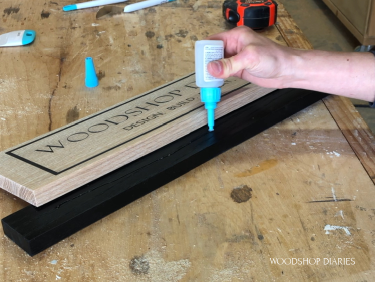 Applying super glue to base plate to attach wooden sign board