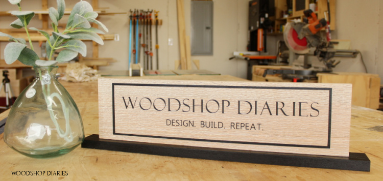 Woodshop Diaries custom sign on base plate sitting on workbench in workshop