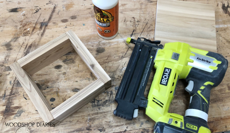 Nail gun and wood glue on workbench used to assemble small square box for lantern base