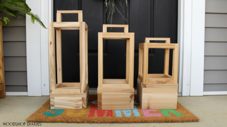 Three sizes of simple outdoor scrap wood lantern sitting on rug in front of front door