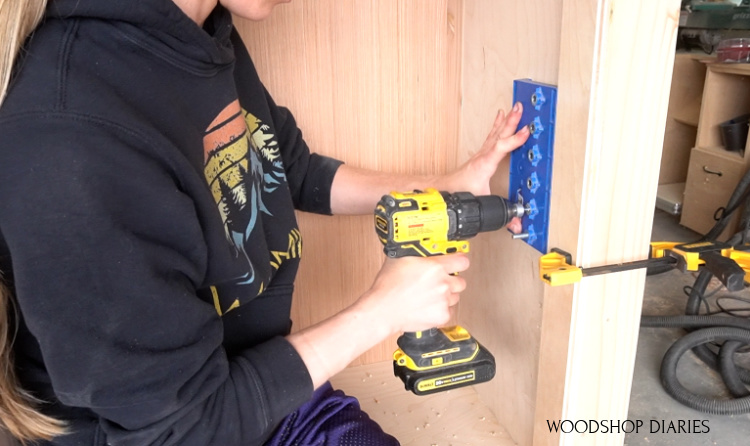 Shara using shelf pin jig to drill shelf pins into sides of cabinet