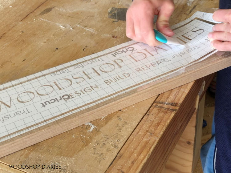 Smoothing out stencil onto wooden sign board