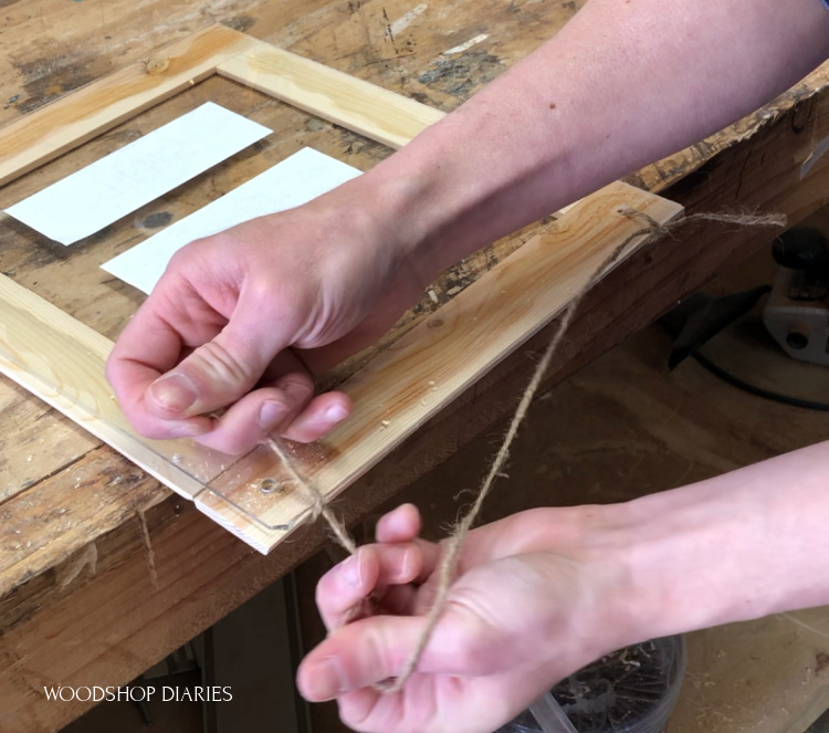 Tying jute rope around top of frame to hang it up