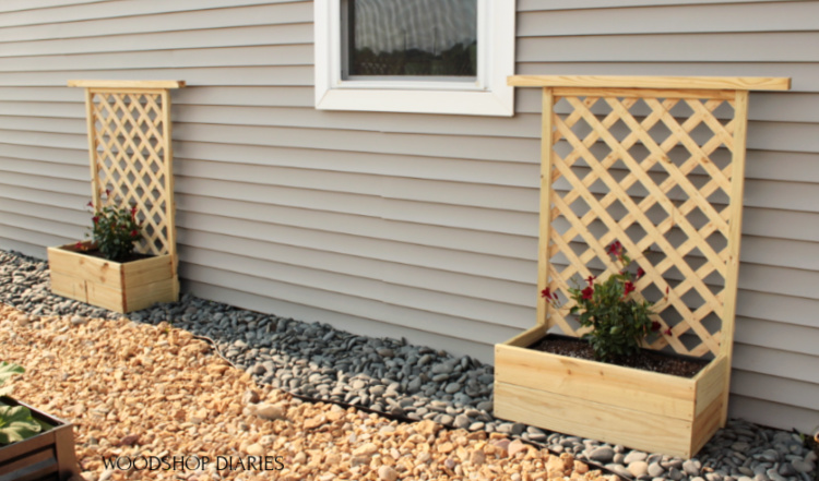 Two completed DIY planter boxes with trellis sitting in garden space next to house