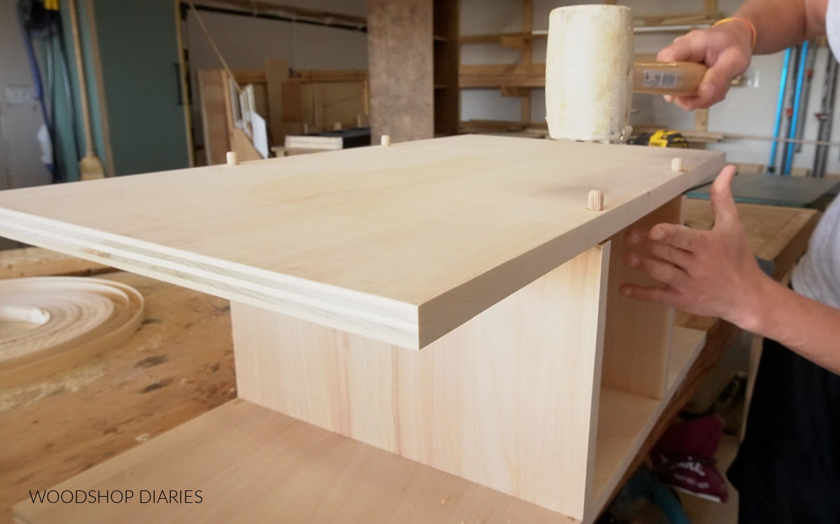 Shara Woodshop Diaries gluing up shoe cubby section with dowels--hammering pieces together in workshop