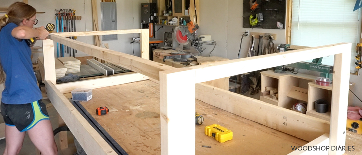 Wide picture of Shara Woodshop Diaries in workshop installing 2x2 supports at top of swing frame using pocket holes and screws