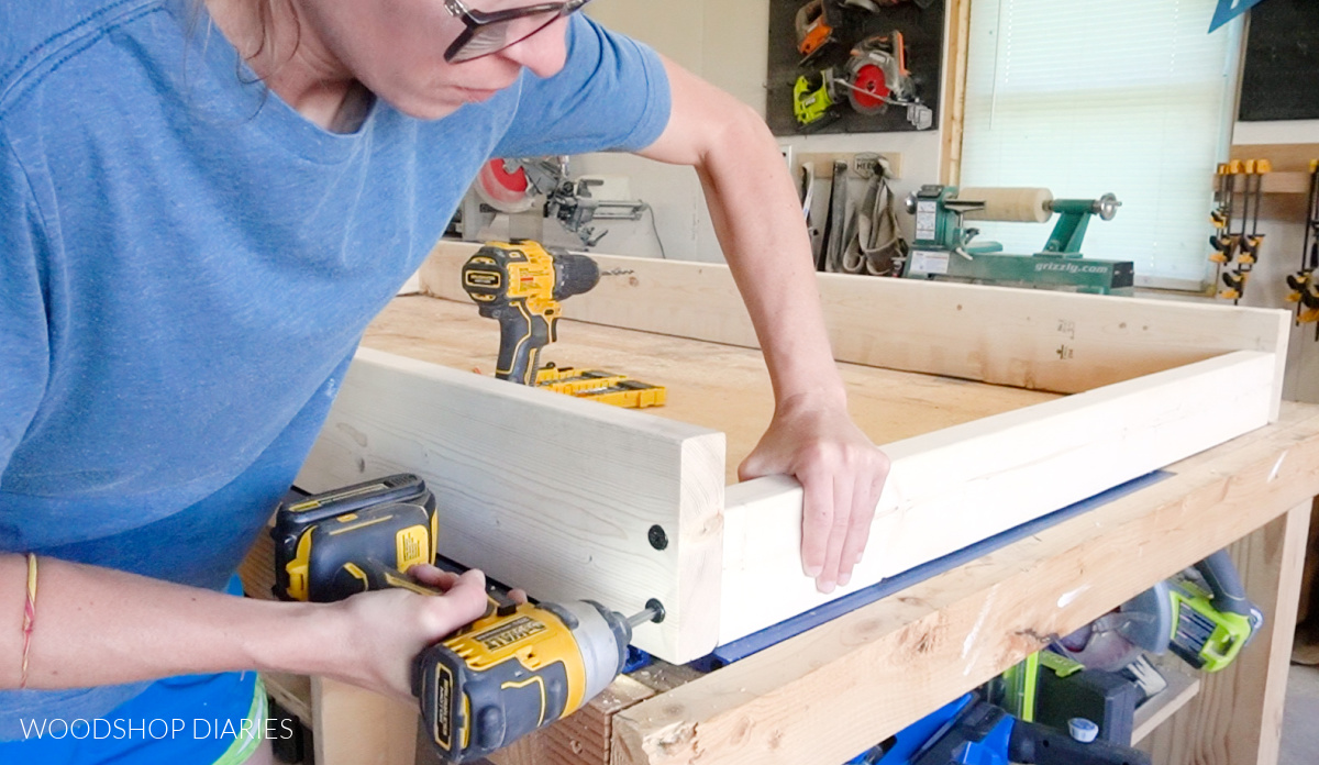 Close up of Shara Woodshop Diaries screwing swing bed seat frame together with timber screws