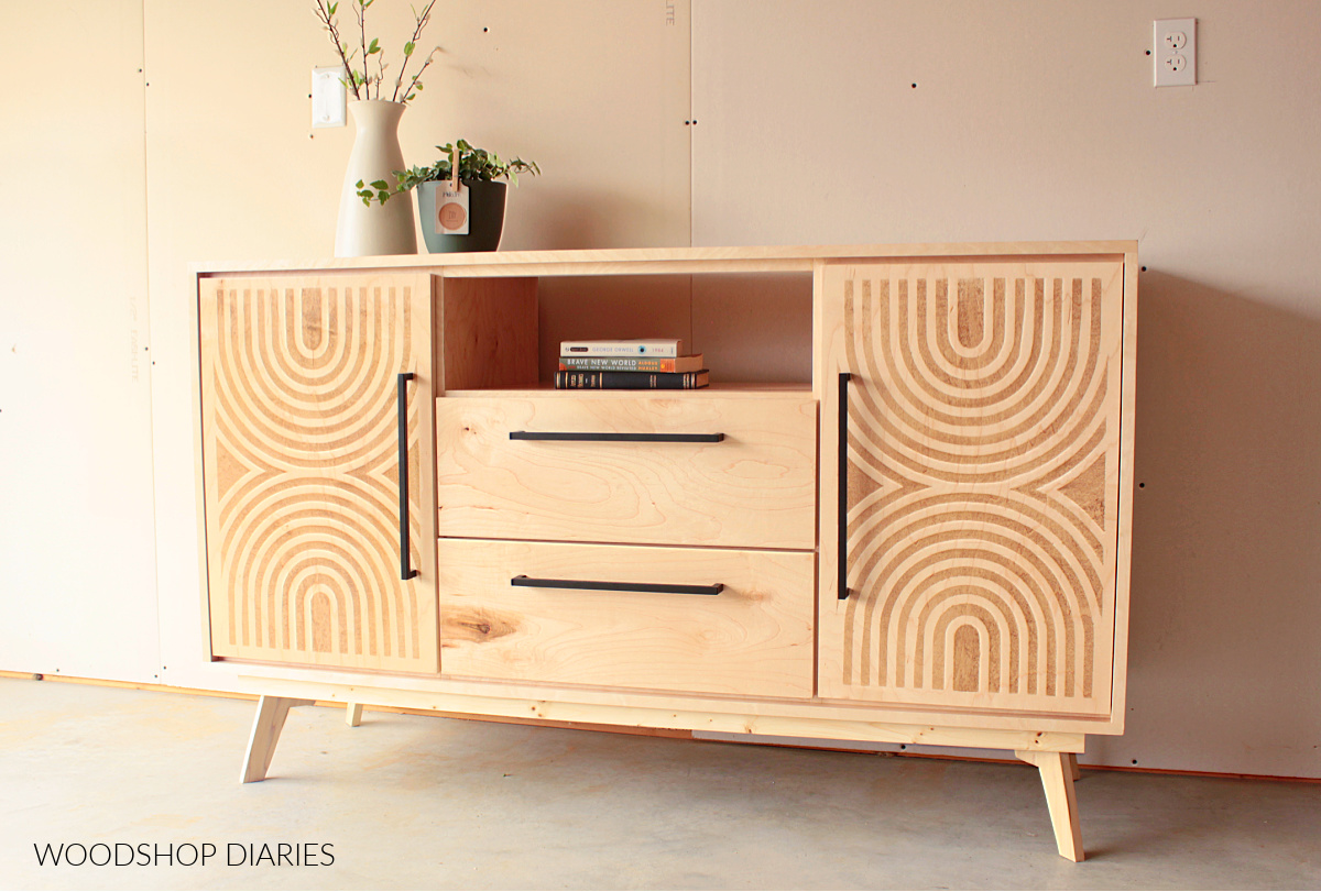 Maple mid century modern console cabinet with doors, drawers, and open shelf. Mid century stenciled doors on left and right