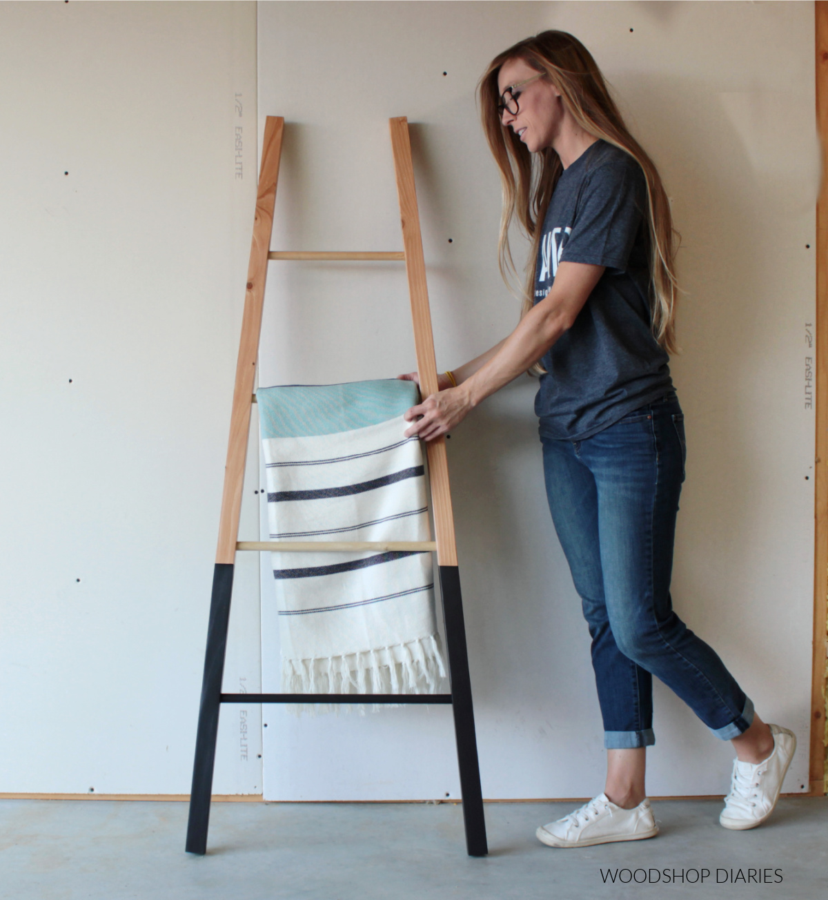 Shara Woodshop Diaries adjusting white and navy striped blanket on two tone DIY wooden blanket ladder