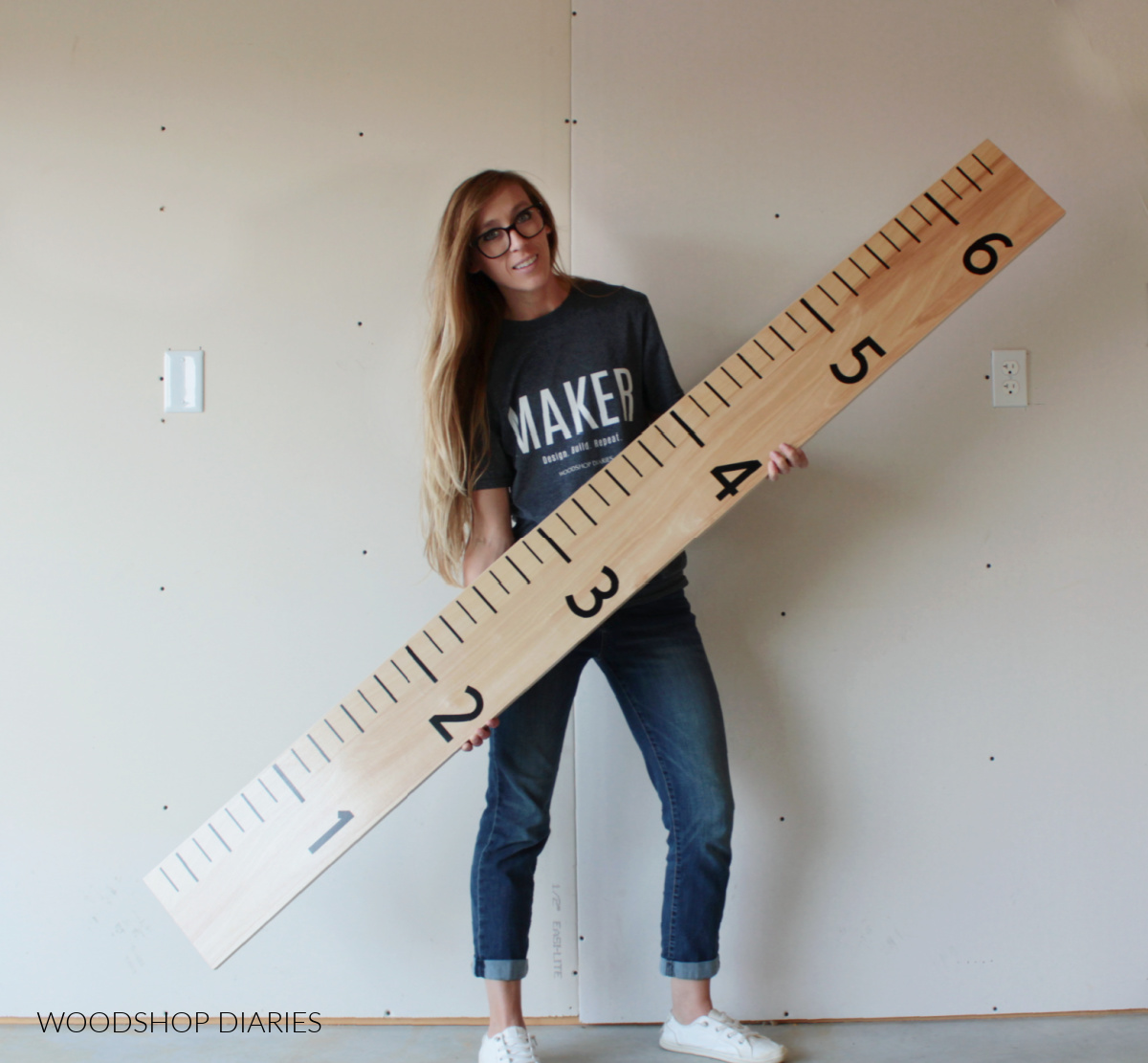 Shara Woodshop Diaries holding life size ruler board