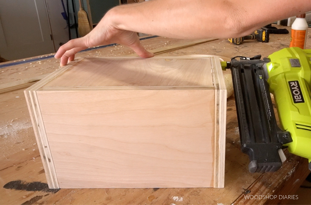 Using nail gun to secure bottom panel through sides