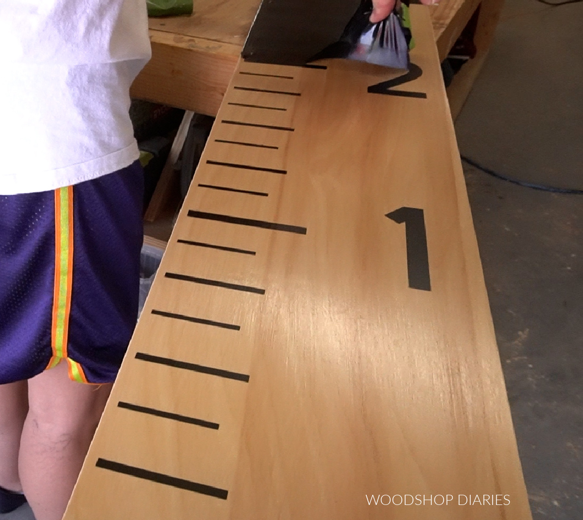 Shara Woodshop Diaries removing vinyl stencil from life size ruler board to reveal marks and numbers
