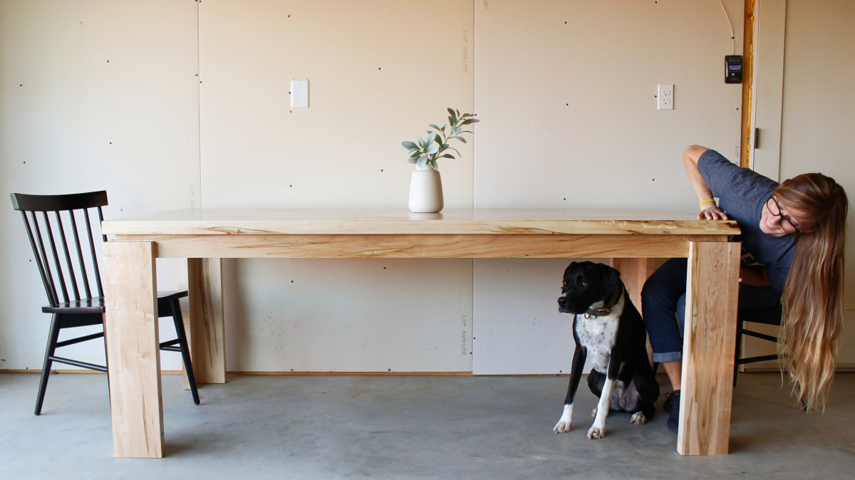 Shara Woodshop Diaries looking at Lucy underneath finished DIY modern dining table
