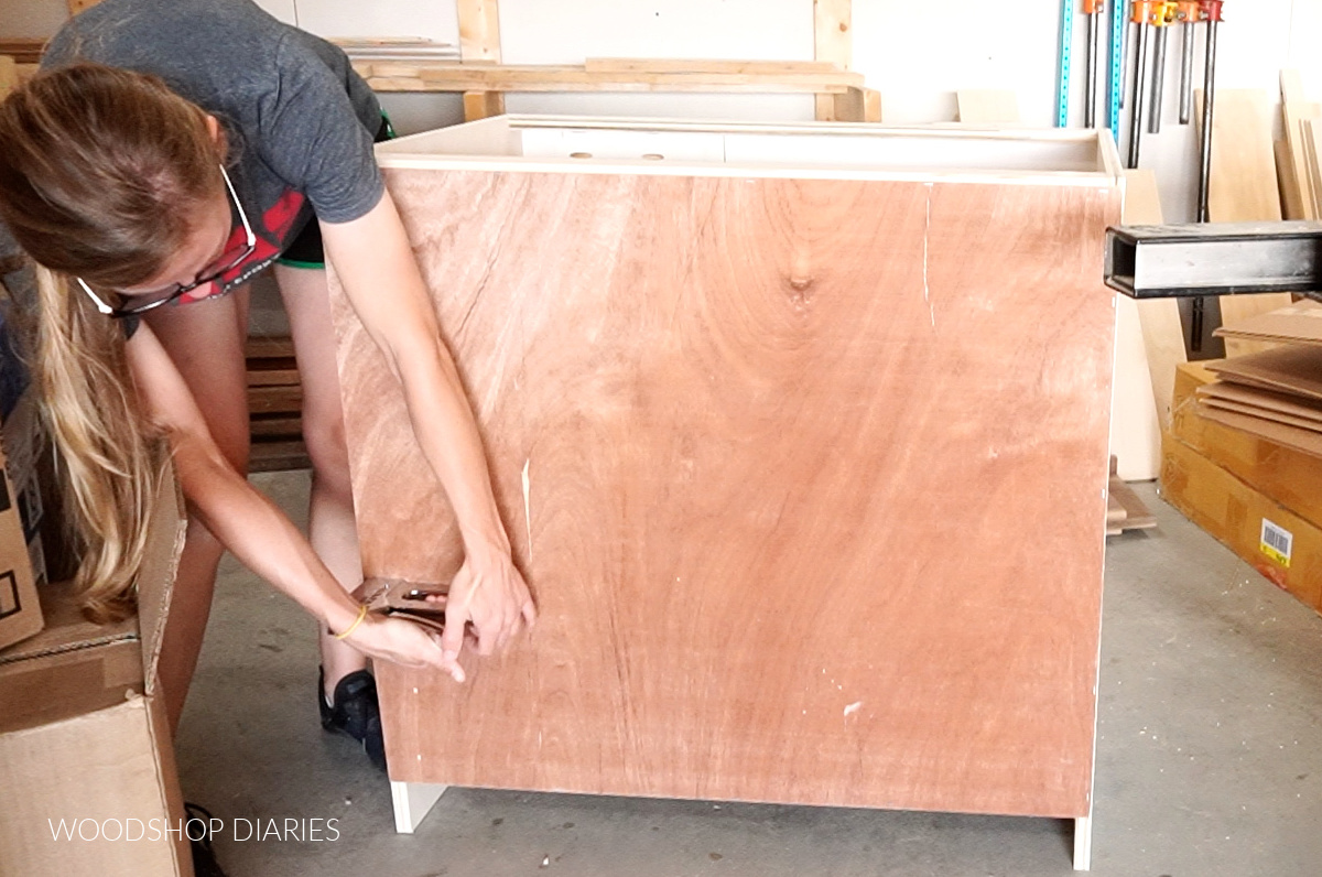 Shara Woodshop Diaries stapling back panel onto cabinet