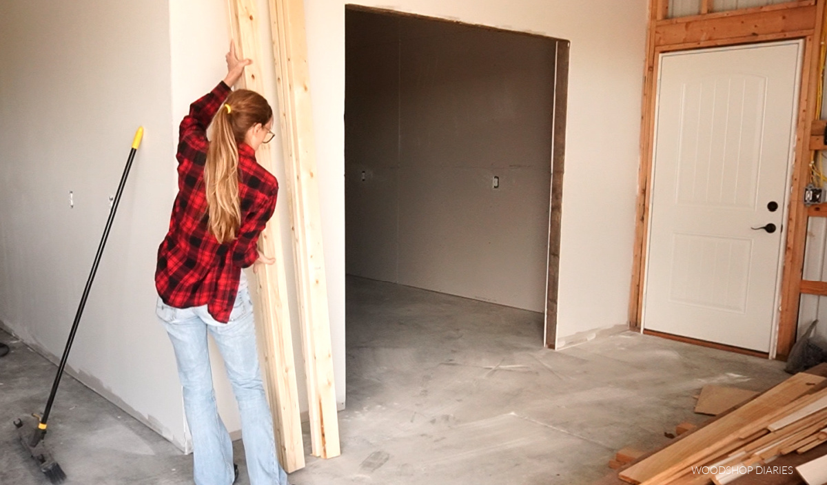 Shara Woodshop Diaries leaning 8 ft 2x4s against the wall to use for lumber rack