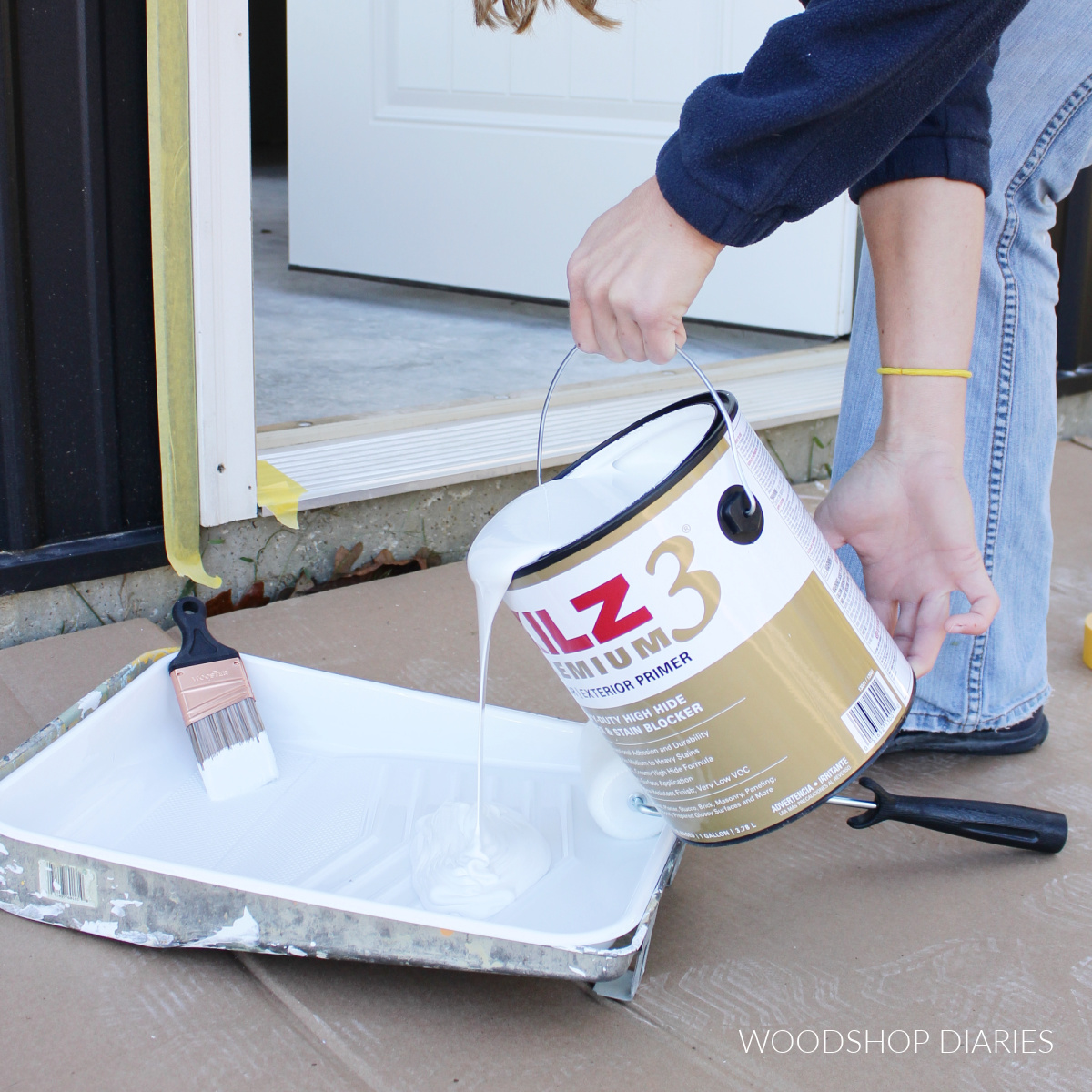 Shara Woodshop Diaries pouring KILZ 3 into paint tray to paint exterior door