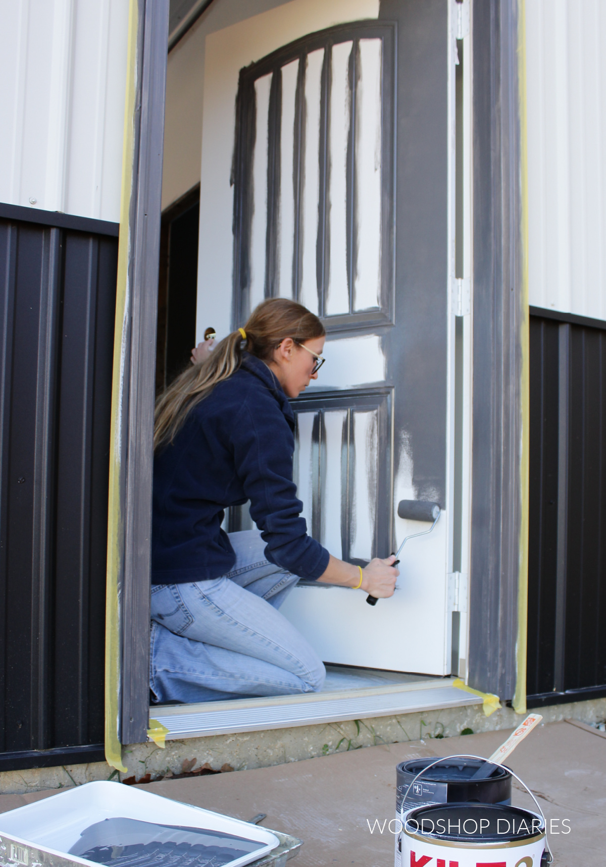 Shara Woodshop Diaries using paint roller to roll paint onto exterior door
