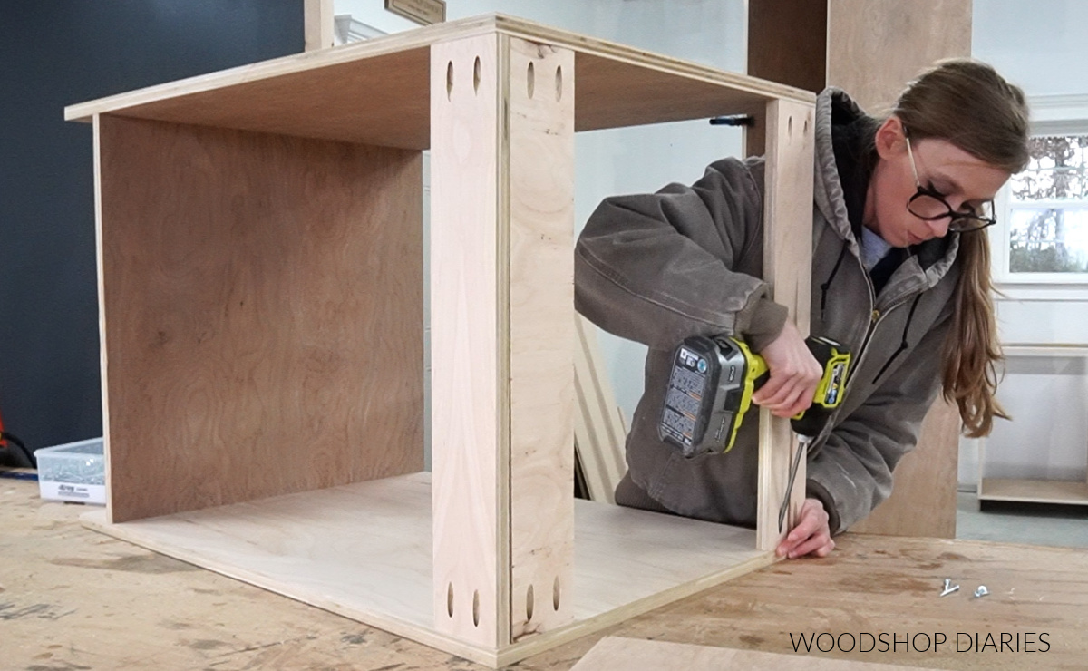Shara Woodshop Diaries assembling a cabinet using a driver and pocket holes on workbench