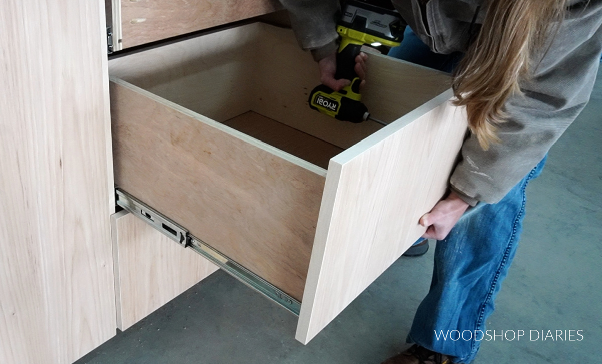 Screwing drawer front onto middle drawer in base cabinet