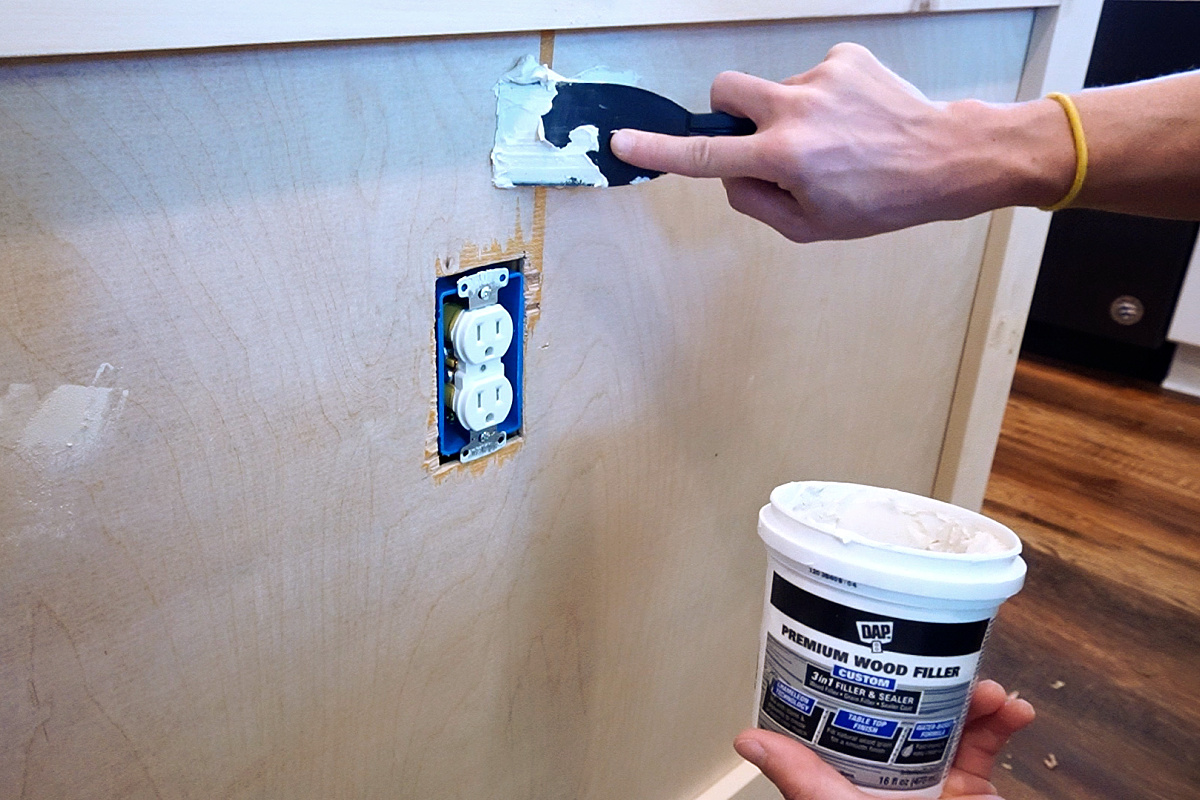 Shara using putty knife to spread DAP Premium Wood Filler on plywood tear out