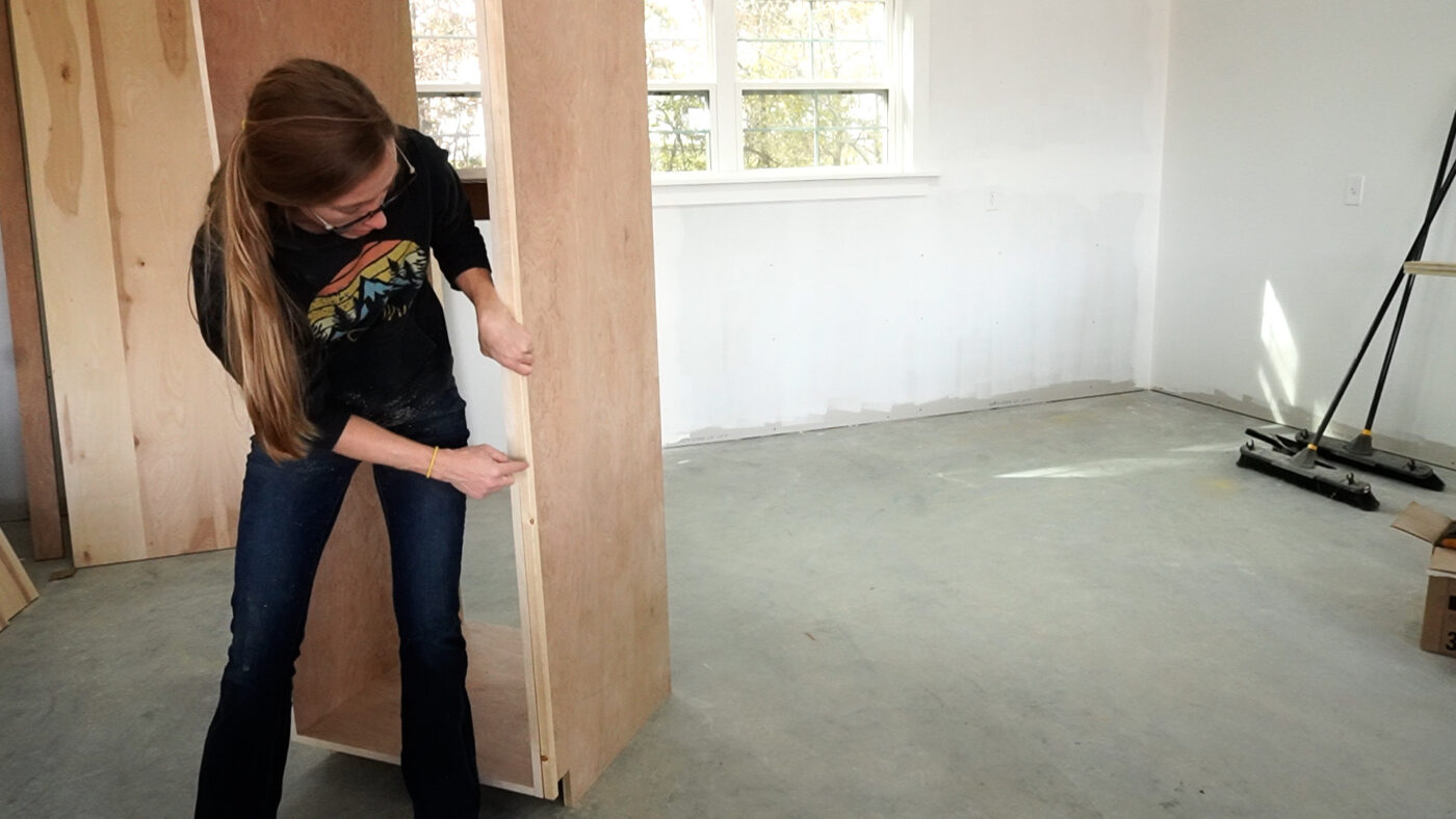 Shara Woodshop Diaries showing attaching a spacer block to prevent baseboard from interfering with cabinet door