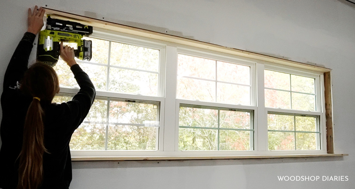 Shara Woodshop Diaries using nail gun to line inside of window frame with 1x4 boards