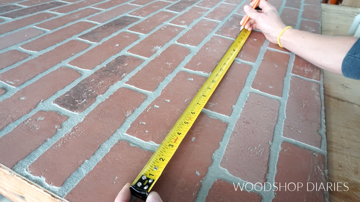 Shara Woodshop Diaries laying out cuts using tape measure to evenly space outside brick pieces