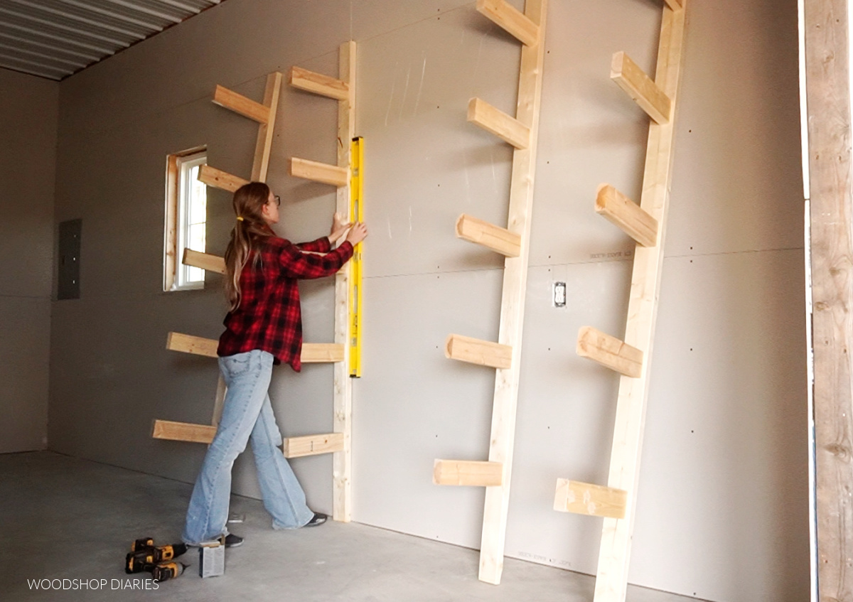 Using a level to ensure backer boards of lumber rack are vertical