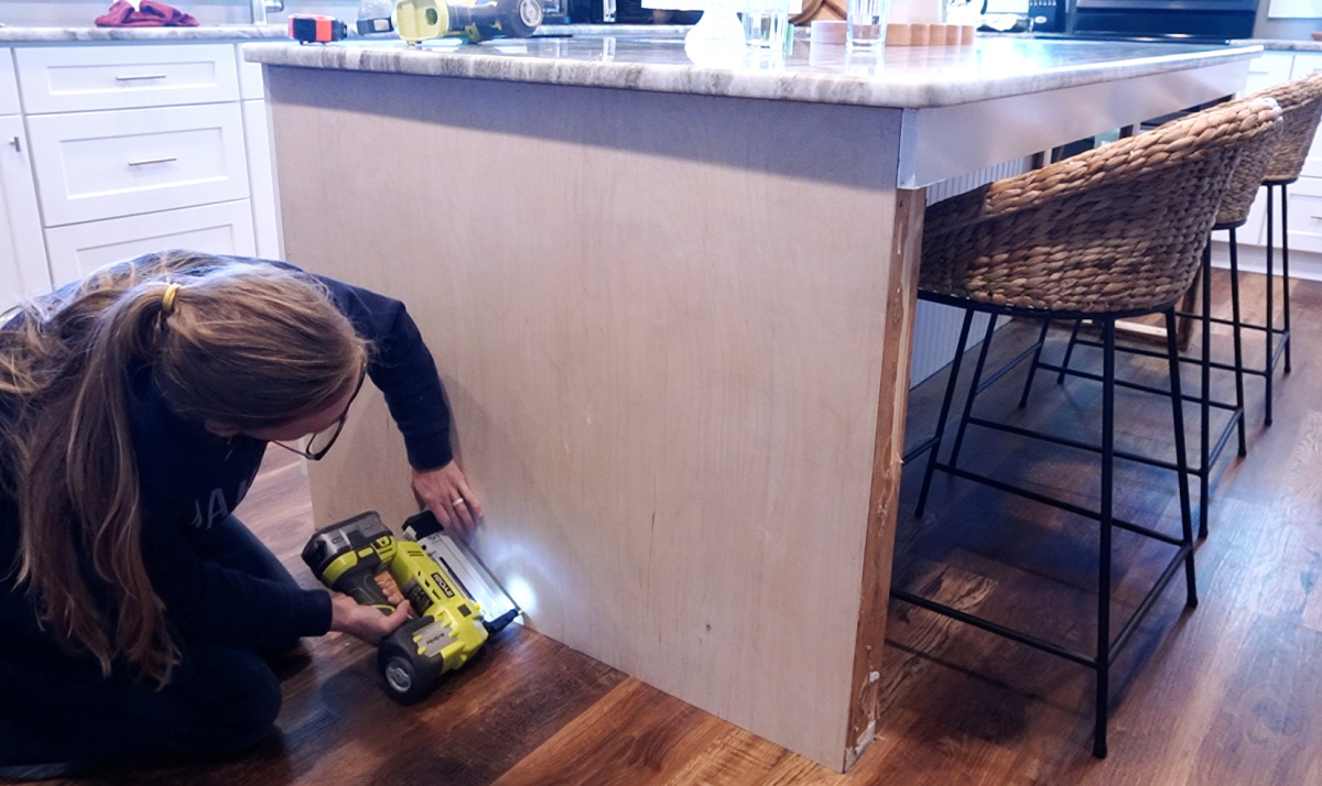 Shara Woodshop Diaries stapling plywood panels onto sides of kitchen island