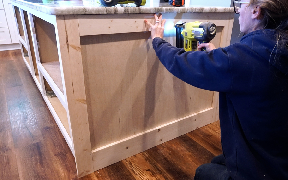 Shara Woodshop Diaries nailing trim pieces onto kitchen island sides