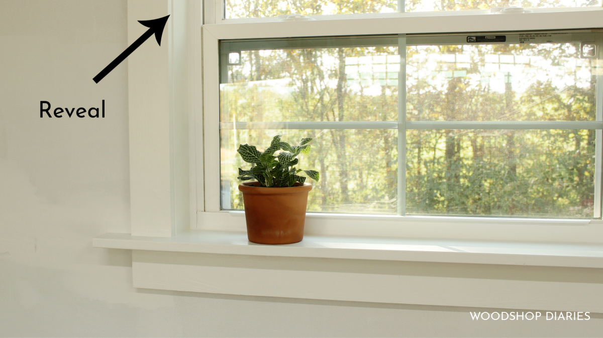 Close up of DIY window trim showing what a reveal is with an arrow pointing
