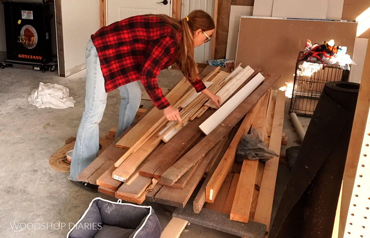 Shara Woodshop Diaries sorting through wood pile on floor of workshop