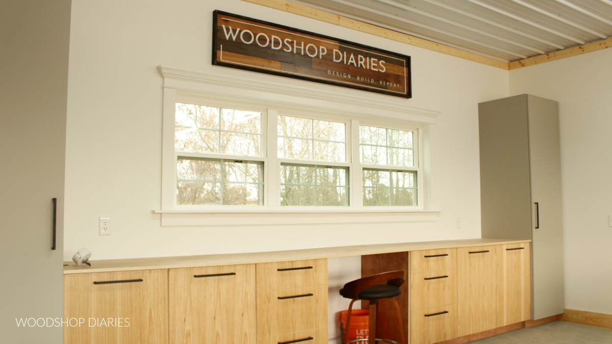 Large wooden sign hanging above windows in workshop with WOODSHOP DIARIES on it