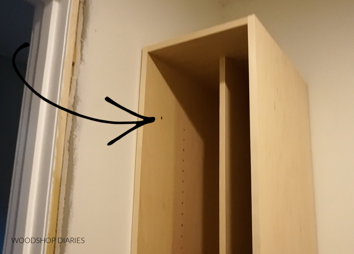 Tall narrow closet cabinet secured to wall stud on side panel