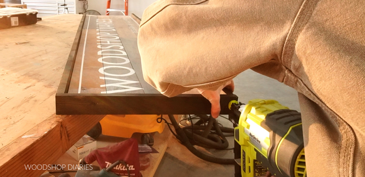Using a finish nailer to attach frame around edges of sign