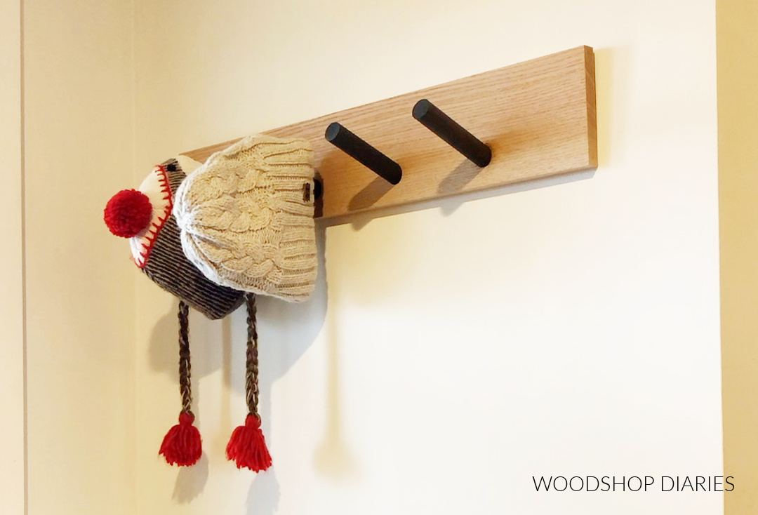 Hats hanging on pegs glued to board--DIY hat rack