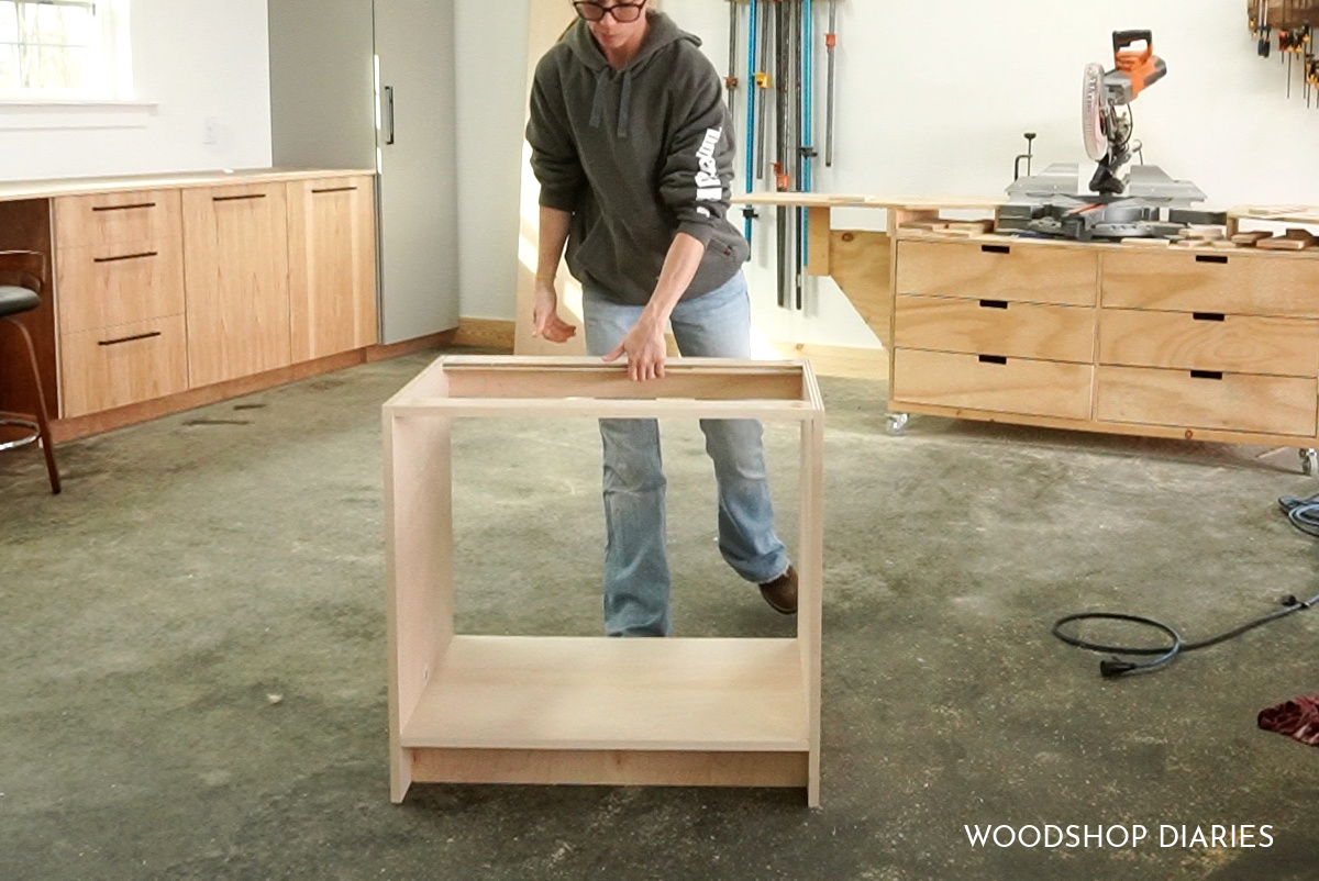 Shara Woodshop Diaries setting plywood desk cabinet on floor of workshop assembled
