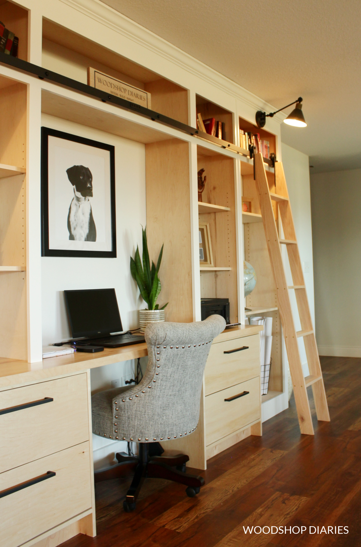 Wood and white painted library bookshelf with rolling ladder and desk in living room space