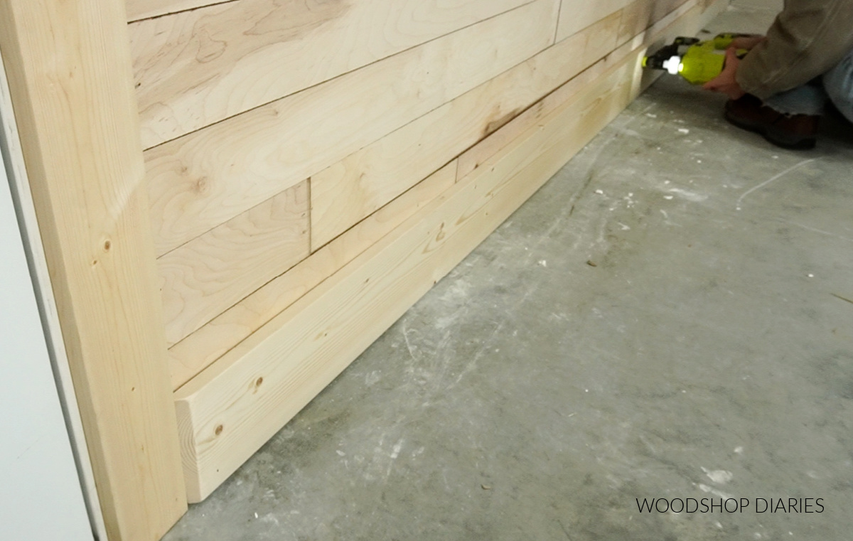 Nailing 1x6 baseboard trim along bottom of wood accent wall