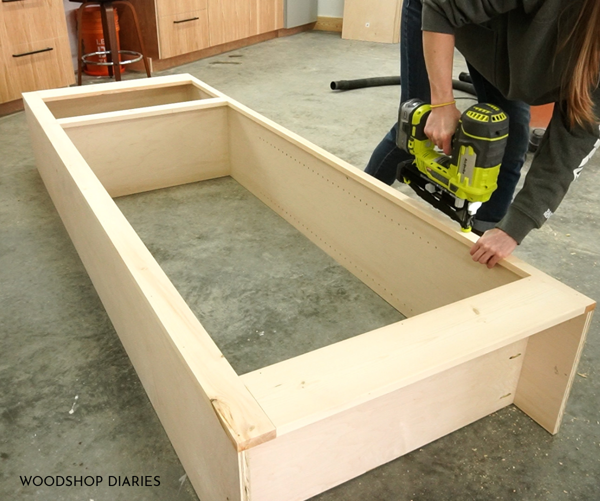 Shara Woodshop Diaries nailing face frame onto the front of large cabinet in workshop