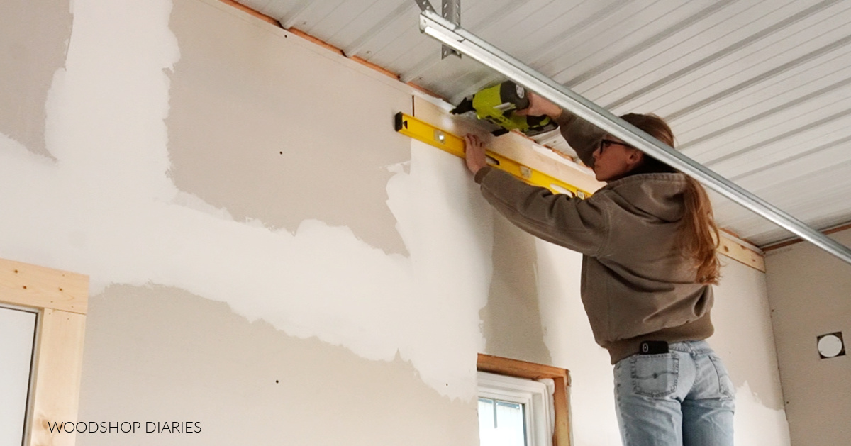 Shara stapling wood planks along top of wood accent wall