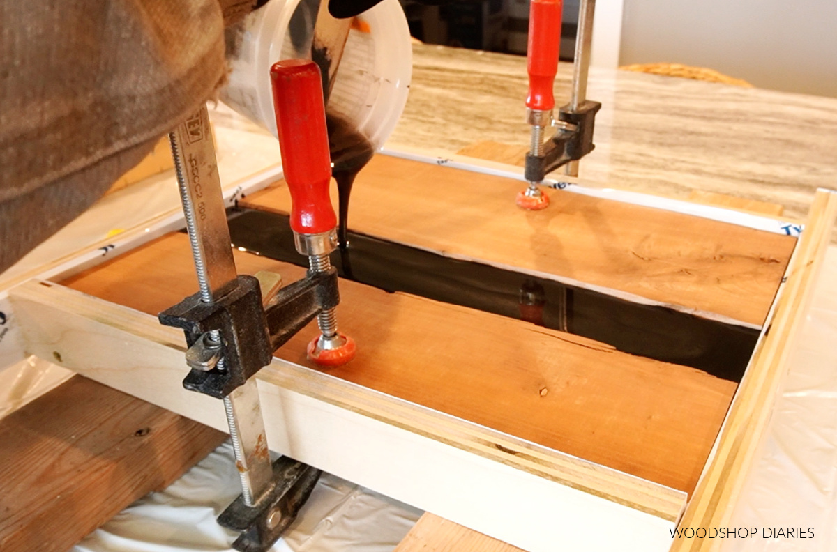 Pouring black resin into mold between two pieces of wood