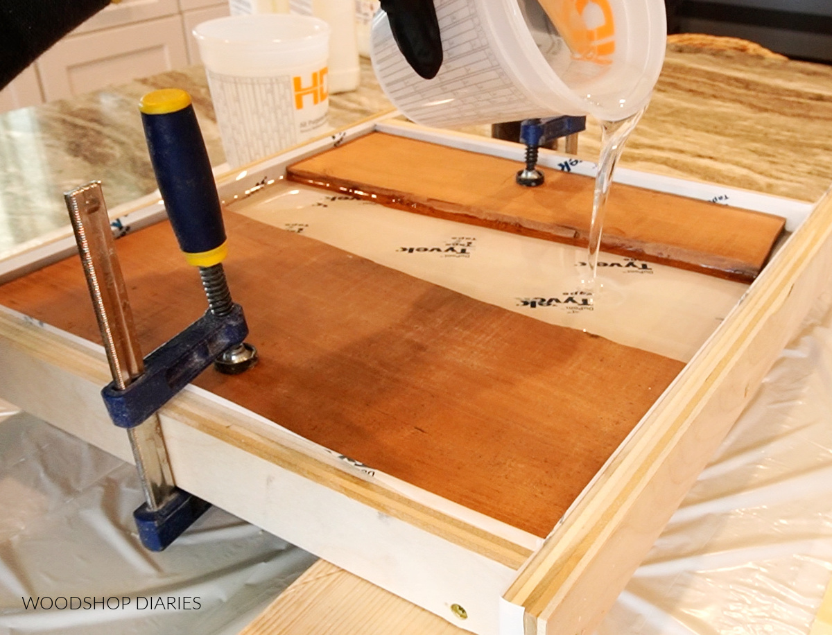 Pouring clear resin into the mold between two pieces of wood