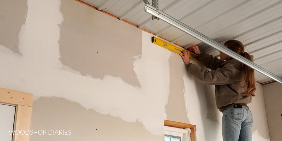 Shara marking level line along top of wall to be planked