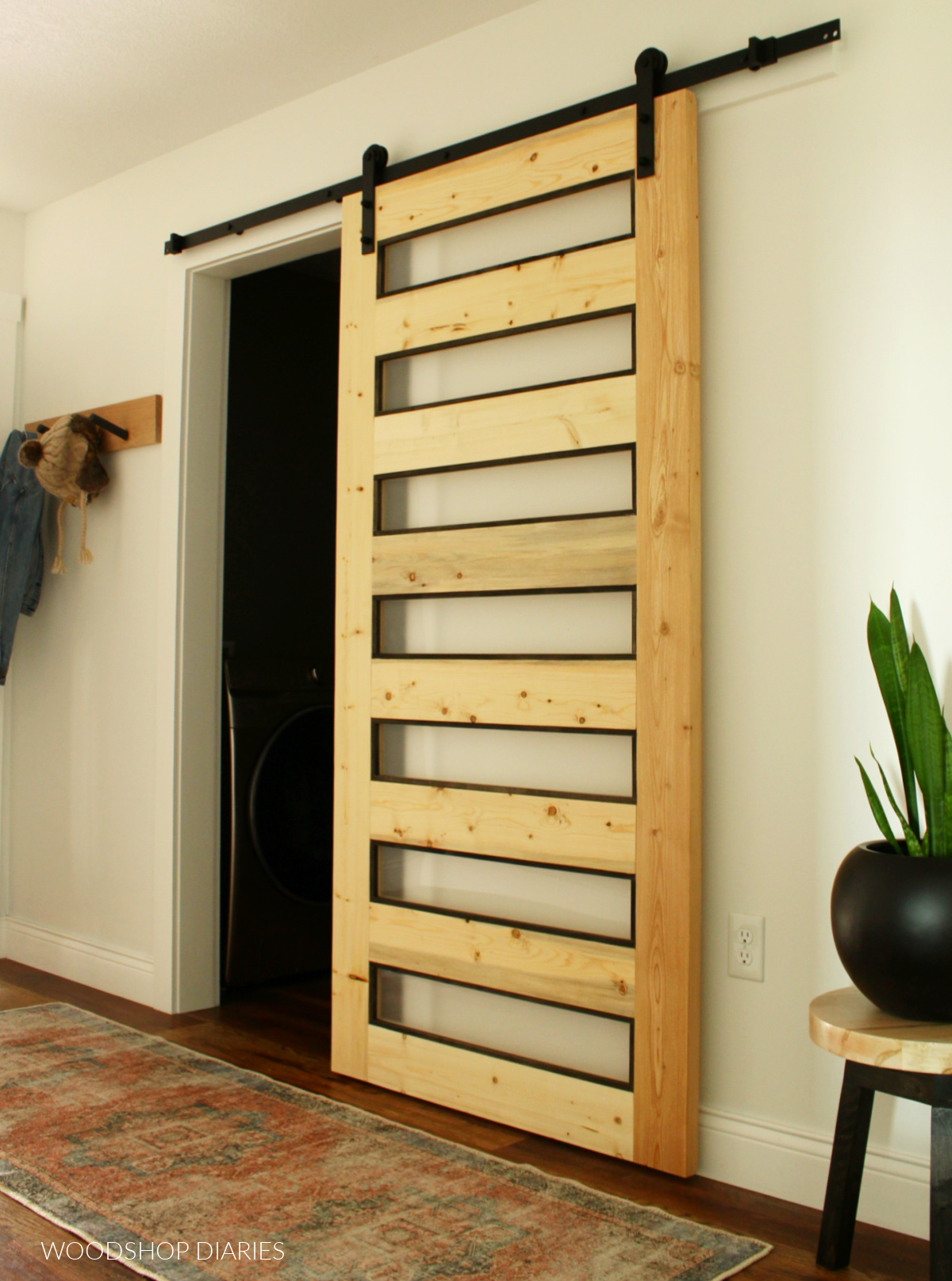 Black and wood modern frosted glass sliding door on laundry room in white hallway