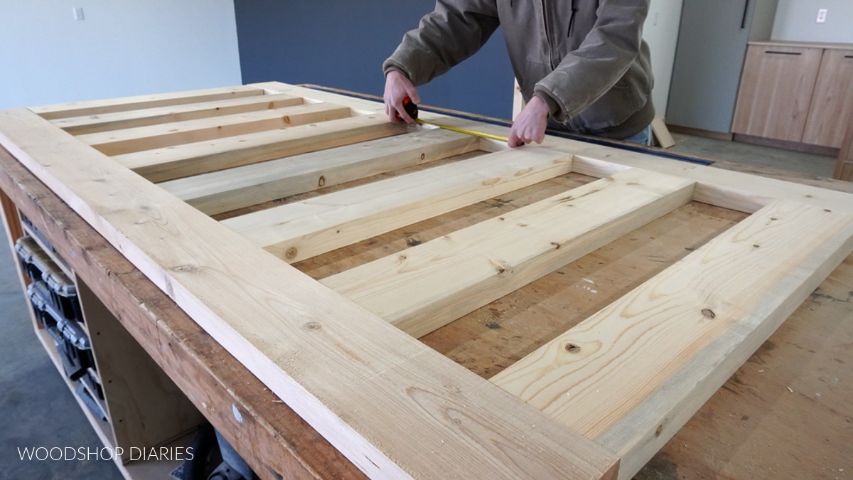 Sliding door frame pieces laid out on workbench--Shara measuring distance between rails